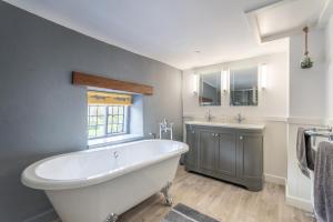 灵伍德Luxury cosy cottage, enchanting forest location.的浴室配有大型白色浴缸和水槽
