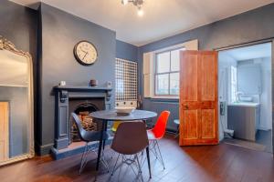 伦敦Trendy 2BD House 5 Mins from Willesden Junction!的一间带桌椅和时钟的用餐室