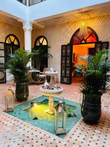 马拉喀什巴马加里亚德酒店的大堂设有喷泉、桌子和盆栽植物