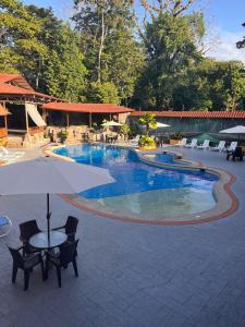 萨拉皮基沨竹萨尔瓦多酒店的一个带椅子和桌子的游泳池以及一把遮阳伞