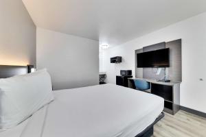 奥斯汀奥斯汀南6号-机场汽车旅馆的一间酒店客房,配有白色的床和一台平面电视