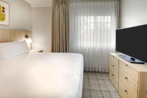 迈阿密Sonesta Simply Suites Miami Airport Doral的配有一张床和一台平面电视的酒店客房