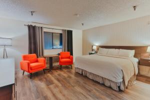 林伍德国际酒店的酒店客房,配有一张床和两张橙色椅子