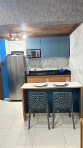萨尔瓦多Maresia 7B的厨房配有桌子、两把椅子和冰箱