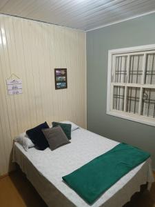 南卡希亚斯Casarão das Figueiras的一间卧室配有一张带绿色枕头的床和一扇窗户