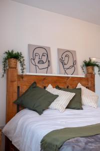 雷纳姆Lovely family home in Rainham, Kent的一张带木制床头板的床,墙上挂着四张照片
