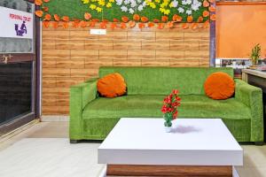 BārangOYO Shibani & Suhani的一张绿沙发,桌子上摆放着橙色枕头