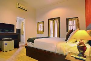 沙努尔普瑞沙丁酒店的一间卧室配有一张大床和电视