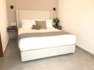 瓜达拉哈拉Urban Chapalita的一张大白色的床,位于带两张桌子的房间