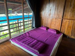 Gia NghĩaKhu Du lịch Nông trại Hải Đăng trên núi的一张位于带紫色床单和枕头的客房的床铺