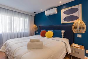 圣保罗Cyclinn Berrini的蓝色卧室配有一张带色彩缤纷枕头的大床
