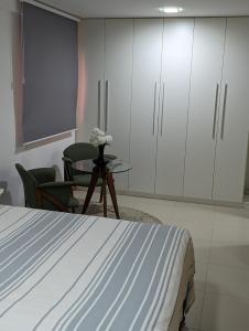 马塞约Moderno apartamento perto da praia的卧室配有一张床和一张桌子及椅子