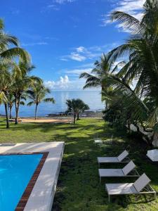 罗驰诺尔Canari Waterfront Villas的拥有游泳池、棕榈树和海洋的度假酒店