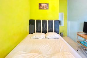 不拉士打宜Penginapan Gindo Sidebuk Debuk Berastagi RedPartner的一张大床,位于拥有黄色墙壁的房间
