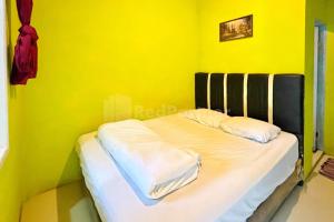 不拉士打宜Penginapan Gindo Sidebuk Debuk Berastagi RedPartner的黄色客房的一张床位,配有两个枕头