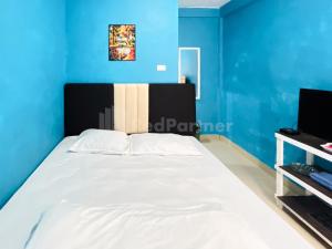不拉士打宜Penginapan Gindo Sidebuk Debuk Berastagi RedPartner的一间卧室设有一张蓝色墙壁的大床