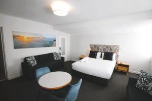 巴特曼斯贝Batemans Bay Lodge的酒店客房带一张床、一张桌子和椅子