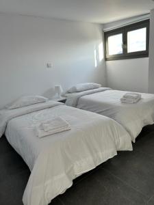 基佩朗达Arxaia skala的白色客房内的两张床和毛巾