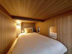 中津川市岩寿莊日式旅馆的一张白色大床,位于带木墙的房间