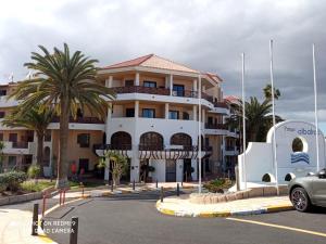 圣米格尔德阿沃纳Las Meninas Tenerife的停车场内一座棕榈树成荫的大型白色建筑