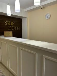 阿斯塔纳Skif Hotel的墙上挂有时钟的酒店接待台
