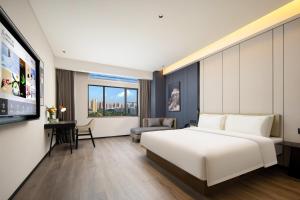 惠州惠州惠阳新都会亚朵酒店的酒店客房设有白色的床和电视。