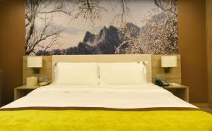 西安西安小寨石油大学亚朵酒店的一间卧室配有一张大床、两盏灯和一幅画