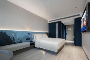 广州广州番禺广场富华东路轻居酒店的卧室配有白色的床和平面电视。