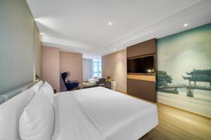 杭州杭州黄龙万科学院路亚朵酒店的卧室配有一张白色大床和一张大画