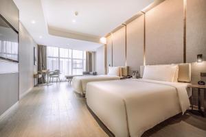 广州广州番禺市桥亚朵酒店的酒店客房设有两张床和一张桌子。