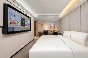 西安西安钟楼大差市地铁站亚朵酒店的卧室配有一张白色大床和一台平面电视。