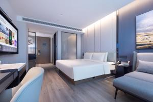 昆明昆明滇缅大道亚朵酒店的卧室配有一张白色大床和两把椅子