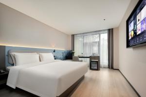 杭州杭州西湖武林广场环城北路轻居酒店的卧室配有一张白色大床和一台平面电视。