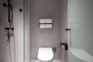 杭州杭州西湖湖滨浣纱路轻居酒店的浴室设有卫生间和带毛巾的淋浴。
