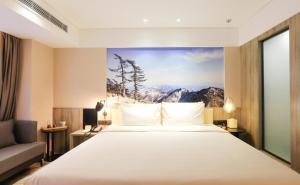 西安西安西咸新区万象城亚朵酒店的酒店客房设有一张床,墙上挂有绘画作品