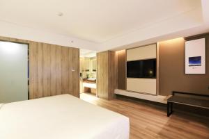西安西安西咸新区万象城亚朵酒店的卧室配有白色的床和平面电视。