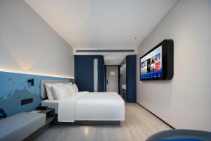 广州广州番禺广场富华东路轻居酒店的配有一张床和一台平面电视的酒店客房