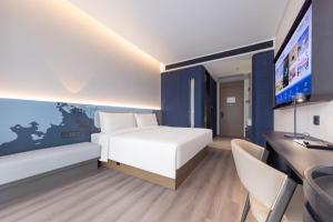 广州广州琶洲会展广州塔地铁站轻居酒店的一间卧室配有一张床、一张书桌和一台电视。