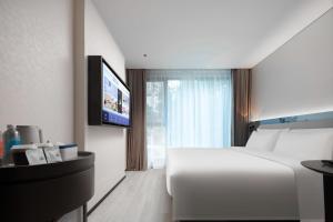 深圳深圳南山来福士广场轻居酒店的一间酒店客房,配有白色的床和一台平面电视