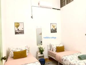 双溪大年Nadialisa cottage homestay For Islamic only的白色墙壁客房的两张床