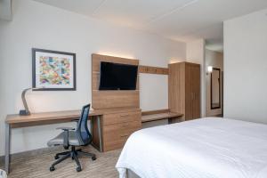 渥太华渥太华机场智选假日套房酒店 的一间卧室配有一张床和一张带电脑的书桌