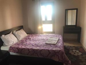 赫尔格达Aldau Heights的一间卧室配有一张带紫色毯子和镜子的床
