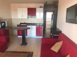 赫尔格达Aldau Heights的一间带红色沙发的客厅和一间厨房
