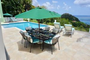Cap EstateLovely 3 BR Ocean View Villa的游泳池旁配有遮阳伞的桌椅