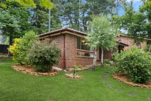 卢拉Azalea Cottage, Leura NSW Australia的院子里两棵树的砖房