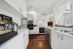 卢拉Azalea Cottage, Leura NSW Australia的厨房配有白色橱柜和黑色家电