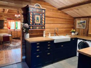 Sjarmerende tømmerhytte på gårdstun的小屋内的厨房配有蓝色橱柜和水槽
