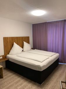费尔德基希Hotel am Bahnhof的紫色窗帘的房间的一张床位