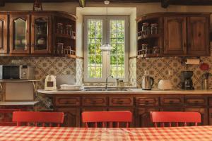 富尔纳斯WelcomeBuddy - O Moinho (Furnas Spring Water)的厨房配有木制橱柜和红色椅子