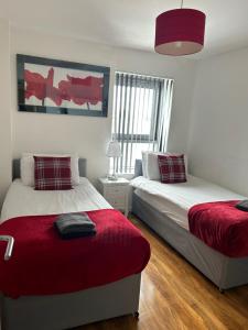 格拉斯哥Riverview Apartments的一间卧室配有两张床和红色毯子